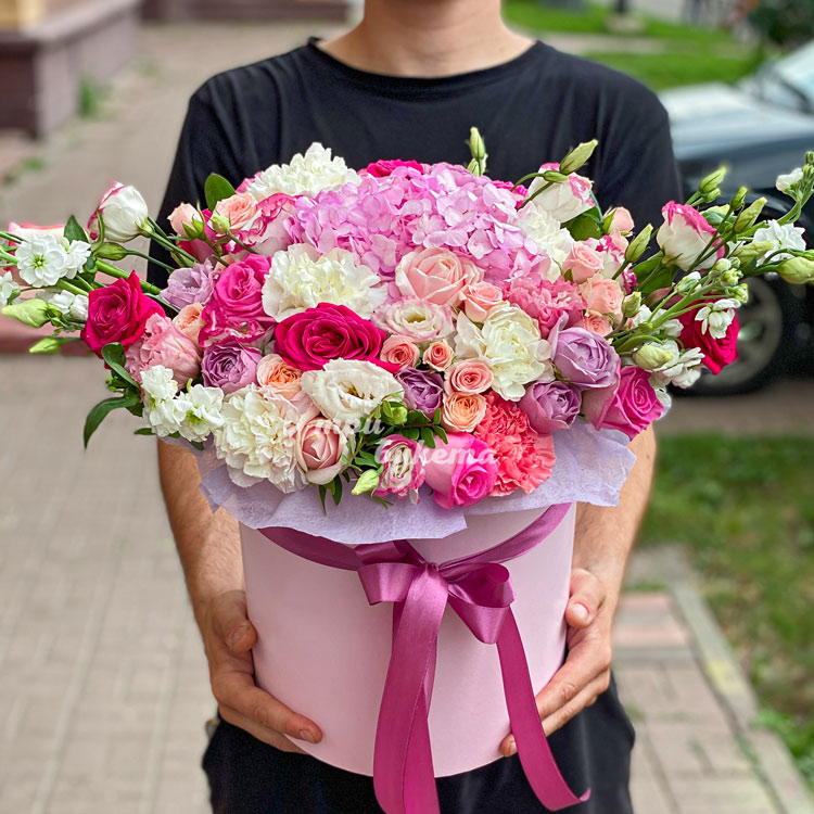 Композиция ярких цветов в шляпной коробке (в руках флориста)